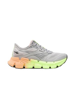 Lichtgrijze Reebok hardloopschoen met mesh bovenwerk, patroonveters en een dikke zool die oranje is bij de hiel en neon groen aan de voorkant.