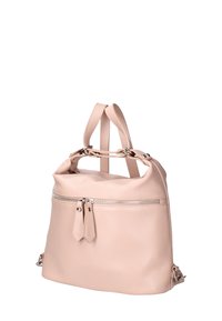 Sac à dos en cuir rose clair avec deux poignées supérieures, un compartiment principal zippé et une poche zippée à l'avant ornée de deux pompons décoratifs.