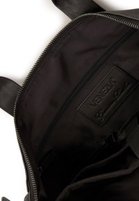 Schwarz lederner Rucksack mit Innenausstattung, die eine Reißverschlusstasche und ein Etikett mit der Aufschrift "VENETIA Echtes Leder" enthält. Weiche Stoffauskleidung.