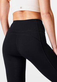 Leggings neri a vita alta realizzati in tessuto elastico, con cuciture piatte e una texture liscia, progettati per comfort e movimento.