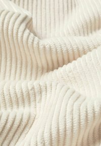 Cremfarbener geripptes Gewebe mit einer weichen, strukturierten Oberfläche, das abwechselnd vertikale Streifen für zusätzliche Details aufweist. Leicht und plüschig.