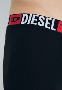 Black boxer briefs with a thick elastic waistband featuring the brand name "DIESEL" in white and red lettering. Smooth texture.
