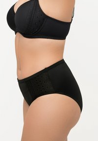 Soutien-gorge noir et culotte taille haute en tissu lisse, avec des accents en dentelle et un panneau à motifs sur les côtés.