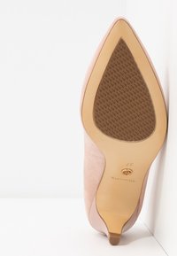 Chaussure femme en daim rose à bout pointu vue de la semelle avec grip texturé et taille 37 marquée sur le talon beige.