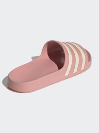Ružová gumová šľapka obsahuje tri biele paralelné pruhy, textúrovanú stielku a hladkú podrážku, s logom 'adidas' na boku.