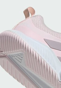 Semelle de basket Adidas rose clair avec motif antidérapant texturé et logo de la marque en dessous, avec tissu tricoté et détails à languette.