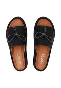 Zwarte instapsandalen met een leren bovenkant, voorzien van een decoratieve strik van metaal. Bruine binnenzool met stiksels.