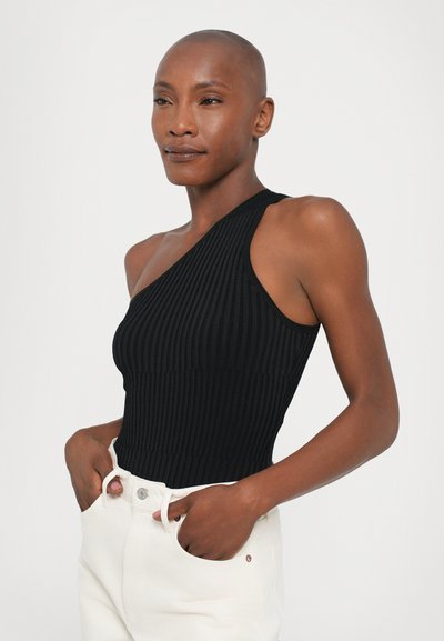 Svart ribbet bodysuit med ensidig design. Glatt tekstur, tettsittende form, paret med hvite bukser med frontlommer og knappelukking.