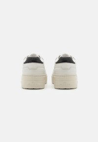 Weiße Sneakers mit einem schwarzen Lederakzent und erhöhtem Sohlenrand. Die Rückseite hat das geprägte Branding "COPENHAGEN" und strukturierte Nähte.