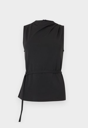 Ermeløs svart topp med høy hals og drapert detalj, med et tynt midjebelte med en metallring på venstre side.