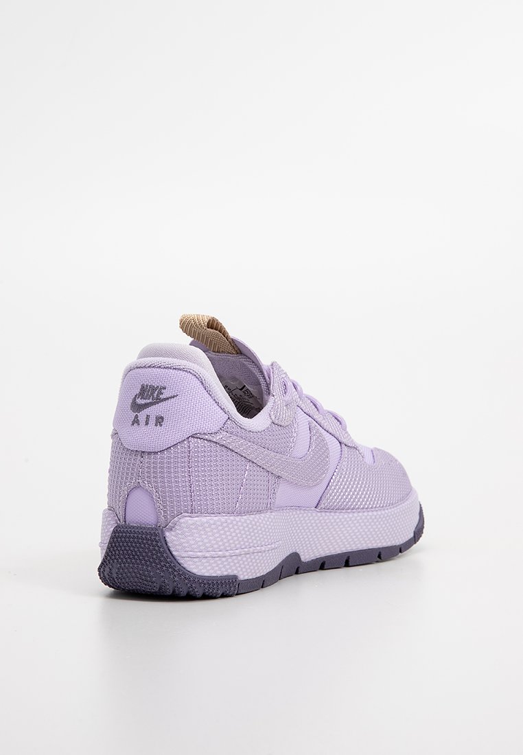 Zapatillas Nike Air en púrpura claro con parte superior de malla texturizada, cuello acolchado y suela de goma púrpura oscura. Presenta el logo en el talón y en el lado.