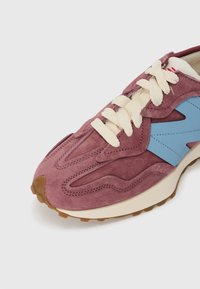 Fialové semišové tenisky s modrými akcentmi, smotanovými šnúrkami a textúrovanou podrážkou. Majú vlnitý dizajn na hornej časti a podrážku z gumy.