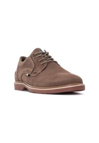 Zapato de ante marrón con cordones y punta redondeada, que presenta una suela de goma en contraste y sutiles detalles de costura.