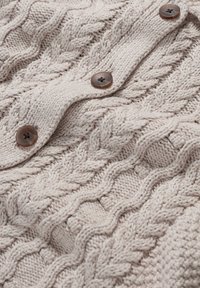 Vaaleanbeige neulottu villapaita, jossa on palmikkokuvio, ja kahdella pyöreällä ruskealla napilla varustettu napitus. Pehmeä, tekstuuriainen kangas.