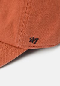 Cappellino da baseball in corduroy arancione con visiera curvata e logo ricamato nero "47" sul lato. Visibile texture del tessuto e dettagli di cucitura.