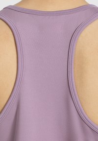 Canottiera sportiva viola con scollo a schiena, spalline larghe e tessuto morbido e elasticizzato. I dettagli delle cuciture arricchiscono il design.