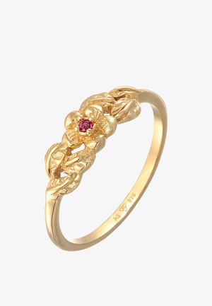 Gold ring featuring a floral design with a central pink gemstone. The band is textured and smooth with intricate detailing.