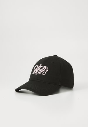 Zwarte katoenen baseballcap met een gebogen vizier; heeft een opvallend roze geborduurd logo op de voorkant; zespanelen ontwerp met een knoop bovenop.
