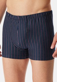 Tmavě modré pruhované boxerky s měkkým elastickým pasem, úzkými vertikálními pruhy v růžové barvě a pohodlným střihem.