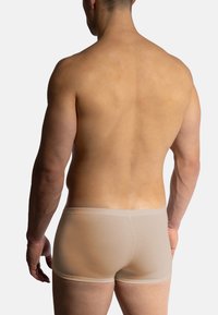 Béžové boxerky vyrobené z elastického materiálu, s měkkým pasem a těsným střihem, pohled zezadu na neutrálním pozadí.