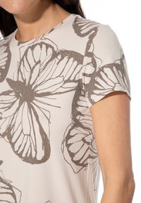 Hellbeiges T-Shirt mit kurzen Ärmeln und großem grauem Schmetterlingsdruck. Weicher Stoff mit glatter Textur und rundem Ausschnitt.