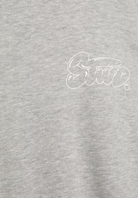 Lysegrå bomulds-T-shirt med blød tekstur, med en hvid grafisk logo i en stiliseret skrifttype nederst til højre.