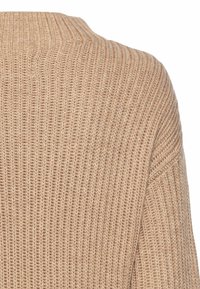 Beige Strickpullover mit strukturiertem Rippmuster, hoher Hals und lockerer Passform, mit Ärmeln, die an den Bündchen schmaler werden.