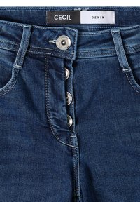 Tummansinisiä farkkuja korkealla vyötäröllä, joissa on viisi nappia edessä ja hienovaraisia ompeluyksityiskohtia.