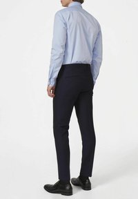 Lichtblauwe overhemd met lange mouwen en een button-down kraag, gecombineerd met smal gesneden donkerblauwe broek en zwarte schoenen. Glad stof, op maat gemaakte pasvorm.