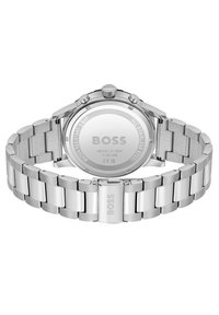Reloj de acero inoxidable plateado con acabado pulido, caja redonda y pulsera de eslabones. Presenta marca grabada y una superficie trasera lisa.