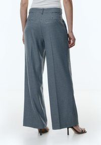 Wijde broek in een zwart-witte houndstooth patroon, gemaakt van een gladde stof met een op maat gemaakte tailleband en zijzakken.