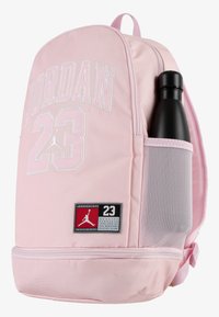 Rosa ryggsekk med "JORDAN" og "23" i hvit brodering, sidelomme til en svart vannflaske og teksturerte grå mesh-detaljer.