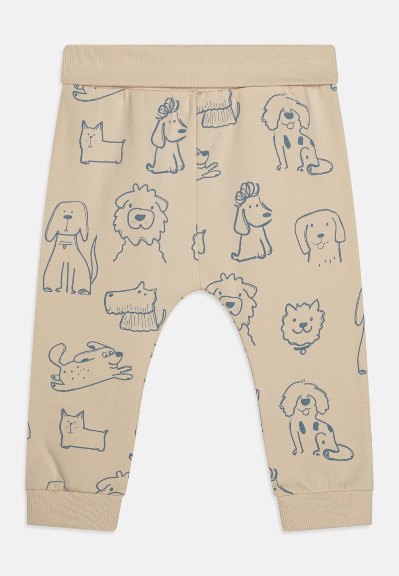 Beige puuvillahousut, joissa on sinisiä koirakuvastoja eri asennoissa, ribbausvyö ja resorit, jotka takaavat mukavan istuvuuden.