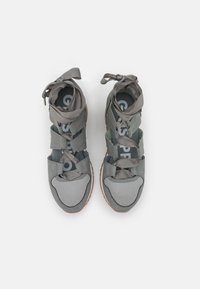Zapatillas deportivas grises con parte superior de malla, correas de tela suave y suela texturizada. Incluyen una marca en color contraste en la plantilla.