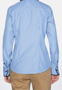 Camisa a cuadros azul y blanca con mangas largas, puños abotonados y cuello abierto. Tejido de algodón con una textura suave.