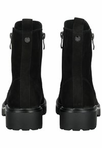 Par de botas de tobillo de ante negro con suelas gruesas, pestañas traseras y cremalleras de metal sobre un fondo blanco.