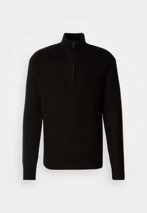 Svart ribbet genser med høy krage og kort glidelås ved halsen; lange ermer og en avslappet passform, laget av teksturert materiale.