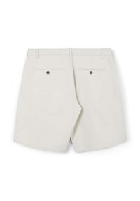 Shorts beiges clairs avec poches arrière et accents en bouton marron, présentant une texture lisse et un design ajusté.