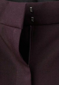 Pantalon en tissu bordeaux avec une texture lisse, une fermeture éclair dissimulée et deux agrafes métalliques à la taille pour un maintien sécurisé.