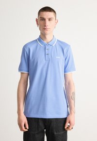 svetlo modra polo majica z belim ovratnikom in poudarki na rokavih, z območjem za tri gumbe in majhnim logotipom "BOSS" na prsih.