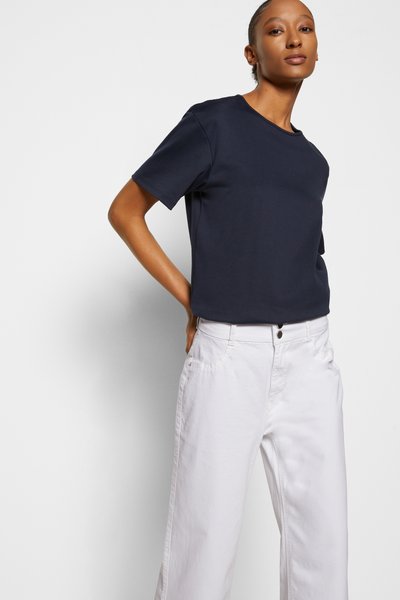 T-shirt de algodão azul-marinho com decote redondo, corte descontraído e mangas curtas, combinado com calças brancas de pernas largas com bolsos.