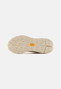 Lightweight trail shoe outsole featuring a rugged, multi-directional tread pattern. Textured cream rubber with a prominent golden logo.