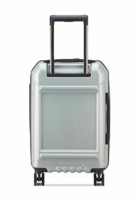 Valigia rigida argentata con manico telescopico esteso e quattro ruote girevoli su uno sfondo bianco.