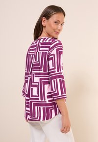 Lichtgewicht blouse in paars en roze met een geometrisch patroon en driekwart mouwen, met een afgeronde onderkant.