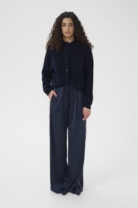Marineblå cardigan med knappelukking, laget av en strukturert strikk, kombinert med vide satengbukser med snøring i midjen.
