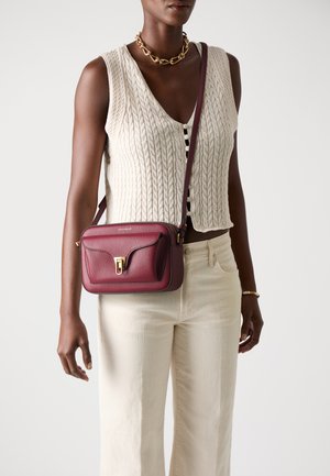 Burgundy leather handbag with a textured finish, rectangular shape, and gold hardware. Features a single adjustable strap and flap closure.
