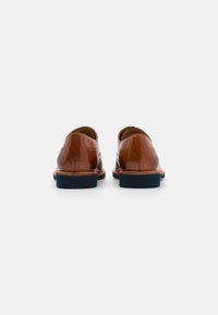 Zapatos de cuero marrón con un acabado suave y puntera redondeada, con una suela de goma azul oscura y detalles de costura mínimos.