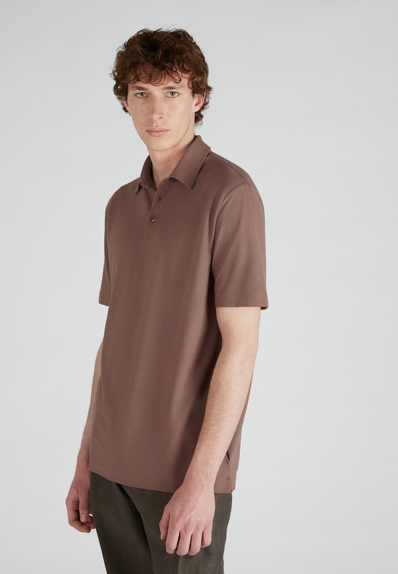 Bruine poloshirt met korte mouwen en een klassieke kraag, voorzien van een drie-knopen placket, gemaakt van zacht, glad materiaal, met een relaxte pasvorm.