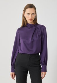 Bluză de satin purpurie cu gât adunat și mâneci lungi bufante, asortată cu pantaloni negri tailoring. Textură netedă, design elegant.