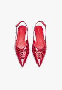 Punaiset nahkaiset slingback-kengät, joissa on terävä kärki, nauhakiinnitys ja silkkinauha edessä. Sileä pinta ja kiiltävä viimeistely.